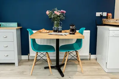 a table with two chairs and a vase of flowers at Annabelle's Den in Gatehouse of Fleet