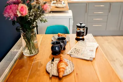 a table with a plate of croissants and a vase of flowers at Annabelle's Den in Gatehouse of Fleet