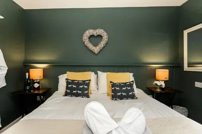 a bedroom with a bed with a heart sign on the wall at Beth's Bothy in Gatehouse of Fleet