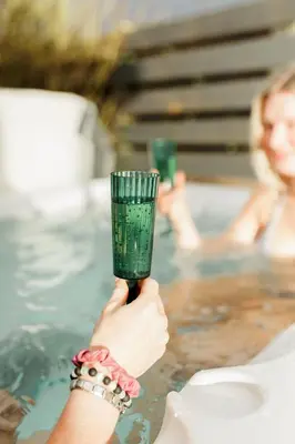 a woman holding a green glass in front of a swimming pool at Beth's Bothy in Gatehouse of Fleet