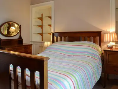 a bed with a colorful striped comforter in a bedroom at Culpee House in Newton Stewart