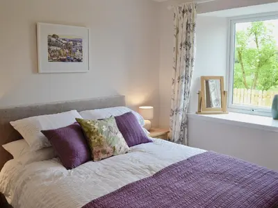 a bedroom with a bed with purple pillows and a window at Swallows in Girthon