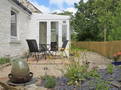 a garden with a table and chairs and a fence at Swallows in Girthon