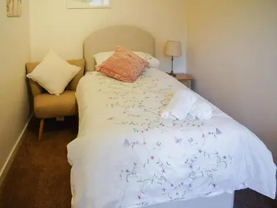 a bed with a white comforter and a chair at The Coach House - Uk30813 in Braithwaite