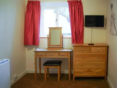 a bedroom with a dresser and a mirror and a window at The Coach House - Uk30813 in Braithwaite