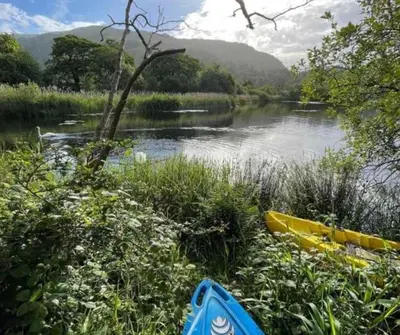 a river with two kayaks on the bank of it at Marys Cottage, Grasmere, Dog Friendly, Hot Tub in Grasmere