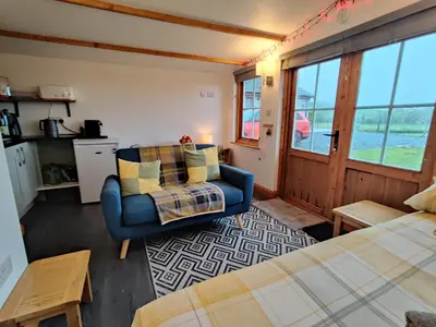 a room with a bed and a chair and a window at Butterfly Cabin in Millom