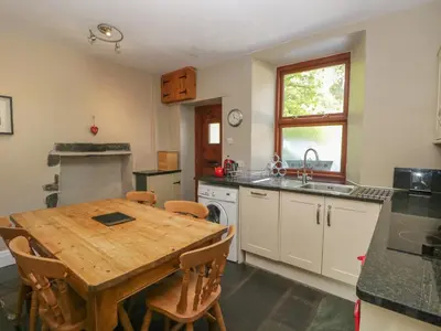 a kitchen with a wooden table and a sink at Acorn Cottage in Coniston