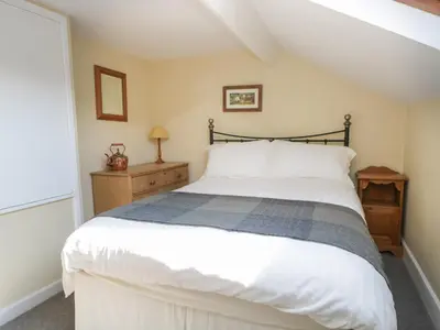 a bedroom with a large white bed and a window at Acorn Cottage in Coniston