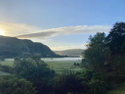a field with fog in the distance with mountains at Foxglove Cottage in Maybole