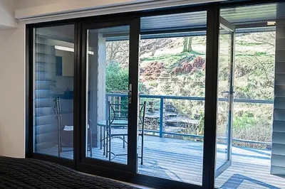 a bedroom with sliding glass doors to a balcony at Tholt-y-Will B&B in Sulby