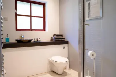 a bathroom with a toilet and a sink and a window at Tholt-y-Will B&B in Sulby
