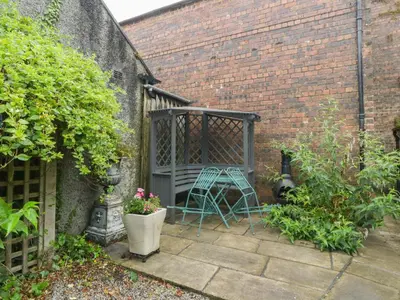 a garden with a bench in a brick wall at The Precinct House in Newton Stewart
