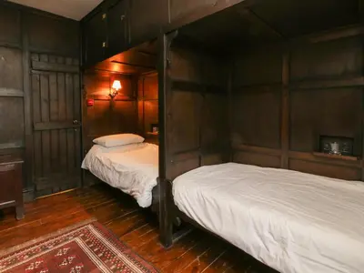 two beds in a room with wooden walls at The Pend in Newton Stewart