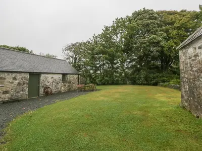 a large yard next to a stone building with a grass yard at Faldarroch Farm in Newton Stewart