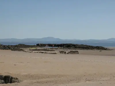 a sandy beach with rocks and the ocean in the background at Sandpiper in Dumfries