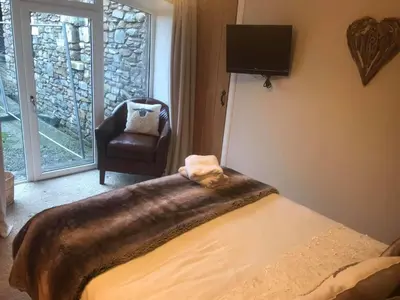 a bedroom with a bed and a chair and a television at The Stables in Castle Douglas