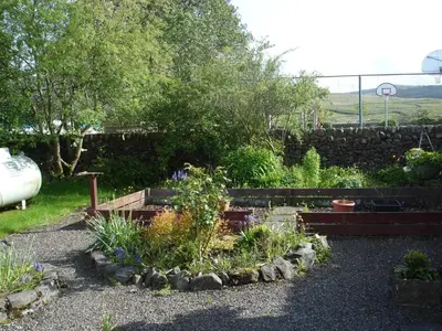 a garden with a stone wall and some plants at RoSE COTTAGE THREE BEDROOM HOUSE WITH PARKING Christmas Special in Carsphairn