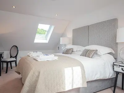 a white bedroom with a large bed and a window at Squirrel Cottage in Stranraer
