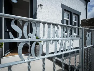 a sign on a fence in front of a house at Squirrel Cottage in Stranraer