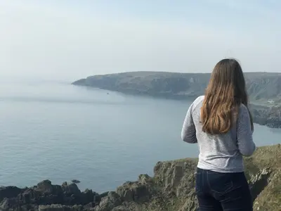 a woman standing on a cliff looking at the ocean at Bunnahabhain 5 - Farm Stay - Stunning sea and rural views in Stranraer