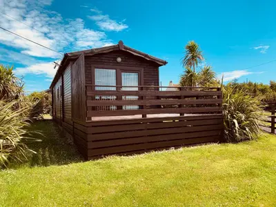a small building with a fence in the grass at Bunnahabhain 5 - Farm Stay - Stunning sea and rural views in Stranraer