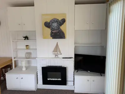 a living room with a fireplace and a picture of a cow at Ardbeg 4 - Farm Stay with Sea Views across to Northern Ireland in Stranraer