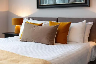 a bed with orange and white pillows on it at Seafield House - Donnini Apartments in Ayr