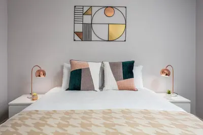 a bedroom with a white bed with two lamps at Seafield House - Donnini Apartments in Ayr