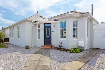a white house with a blue door at Seafield House - Donnini Apartments in Ayr
