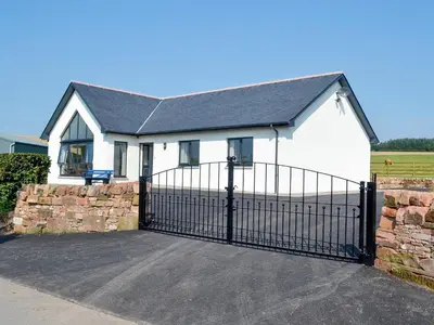 a white house with a gate and a fence at Auchen Ladder in Amisfield Town