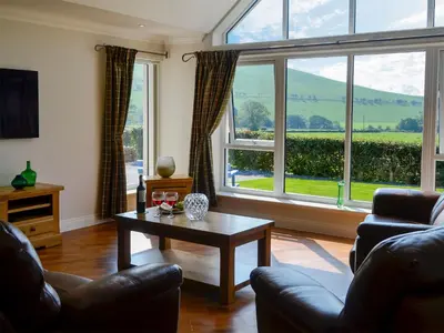 a living room with a table and a large window at Auchen Ladder in Amisfield Town