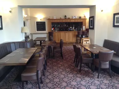 a restaurant with tables and chairs and a bar at Arden House Hotel in Kirkcudbright