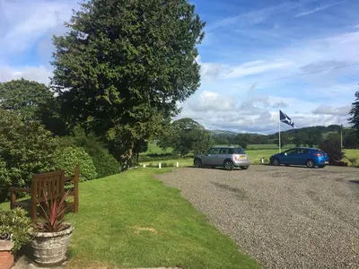 two cars parked on the side of a gravel road at Arden House Hotel in Kirkcudbright