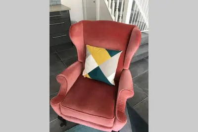 a red chair with a colorful pillow on it at Albion Cottage in Cockermouth