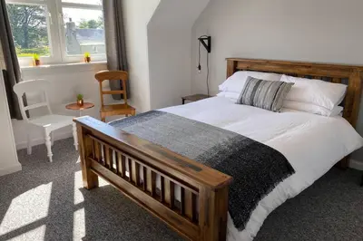 a bedroom with a large bed and a window at 2 Calgow Cottages in Newton Stewart