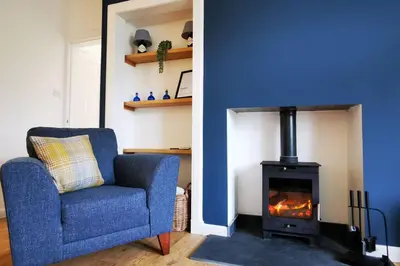 a blue room with a chair and a fireplace at 2 Calgow Cottages in Newton Stewart