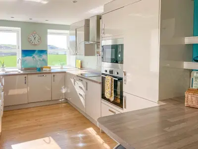 a kitchen with white cabinets and a clock on the wall at Ardstinchar Mews in Ballantrae