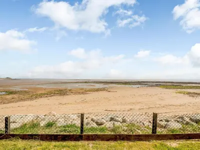 a fence in the middle of a field with a beach at Sand View in Mainsriddle