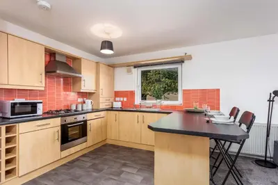 a kitchen with wooden cabinets and a black counter top at Walker Suite No82 - Donnini Apartments in Kilmarnock