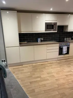 a kitchen with white cabinets and a wooden floor at Kezbah2 22 the square centre of Dalston village in Dalston