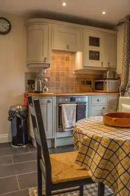 a kitchen with white cabinets and a table with a table cloth at Reayrt Ny Marrey in Kirkmichael