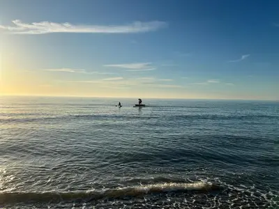 two people in the ocean on surfboards in the water at Reayrt Ny Marrey in Kirkmichael