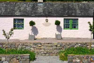 a white building with two windows and a green door at The Munches Room at Buittle Castle in Castle Douglas