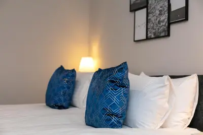 two blue pillows sitting on top of a bed at Seaforth Suite - Donnini Apartments in Ayr