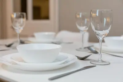 a table with white plates and wine glasses on it at Seaforth Suite - Donnini Apartments in Ayr