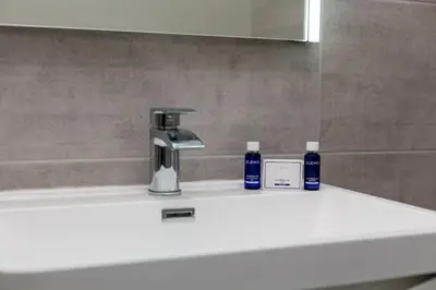 a bathroom sink with a faucet and two bottles on it at Seaforth Suite - Donnini Apartments in Ayr
