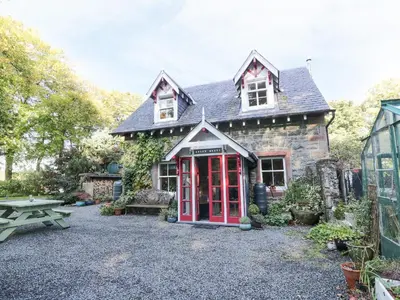 a house with a red phone booth in front of it at The Coach House in Newton Stewart