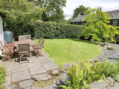 a patio with chairs and a table in a yard at Garden Cottage in Threlkeld