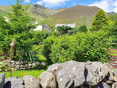 a garden with rocks and trees and a mountain at Garden Cottage in Threlkeld